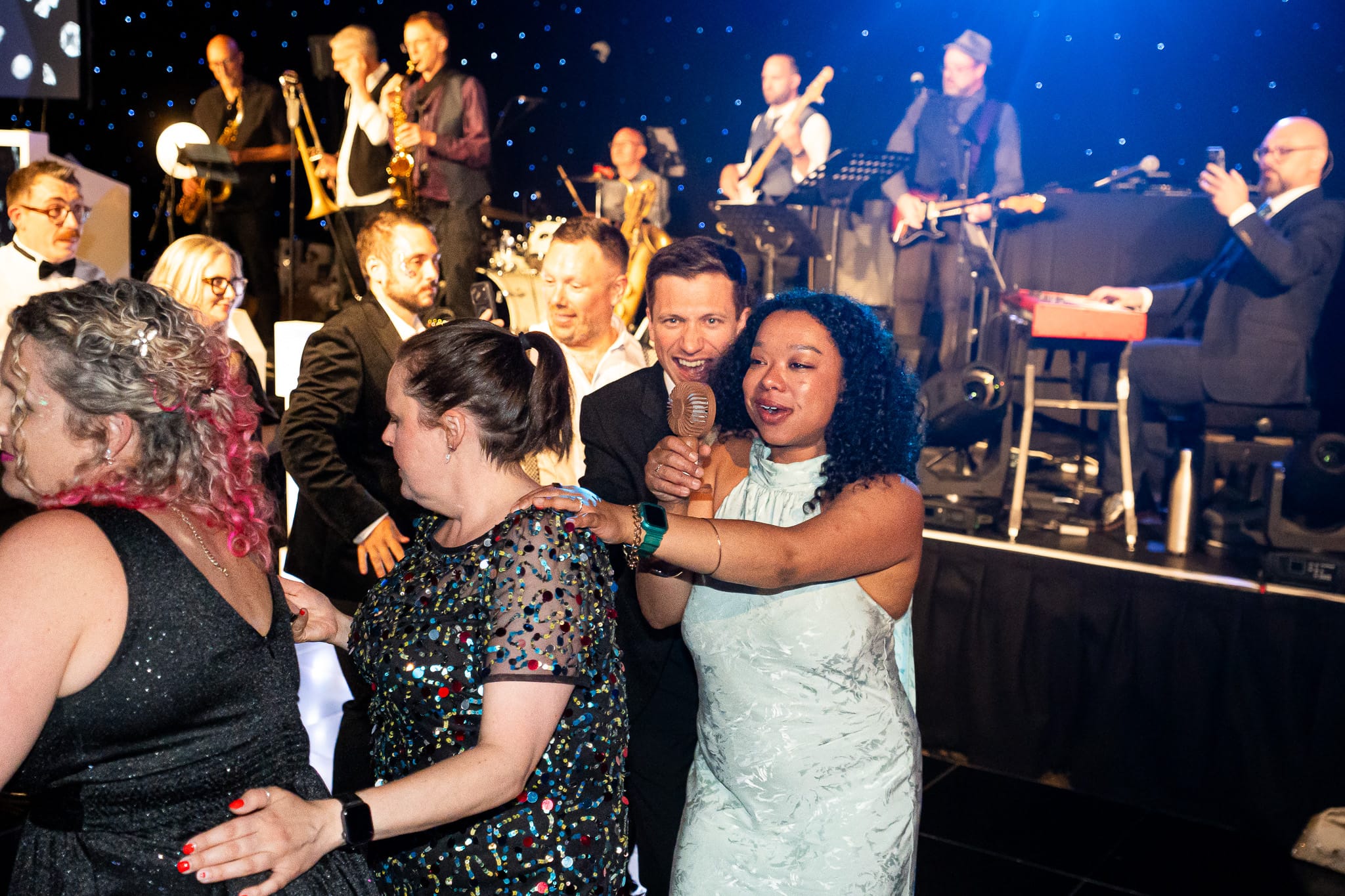 Guests singing and dancing together beside the live band
