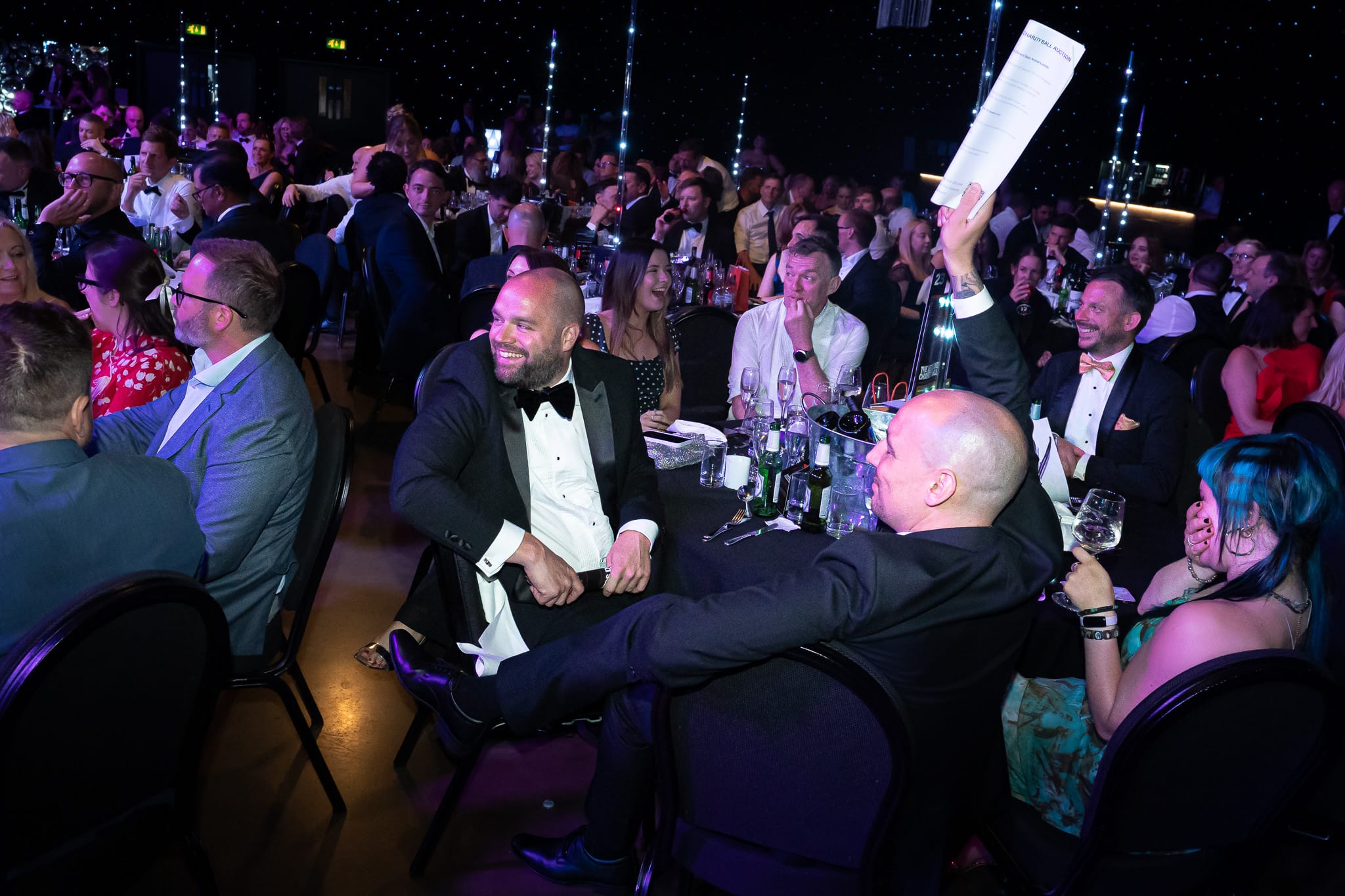 Guests smiling and laughing around a busy charity ball table