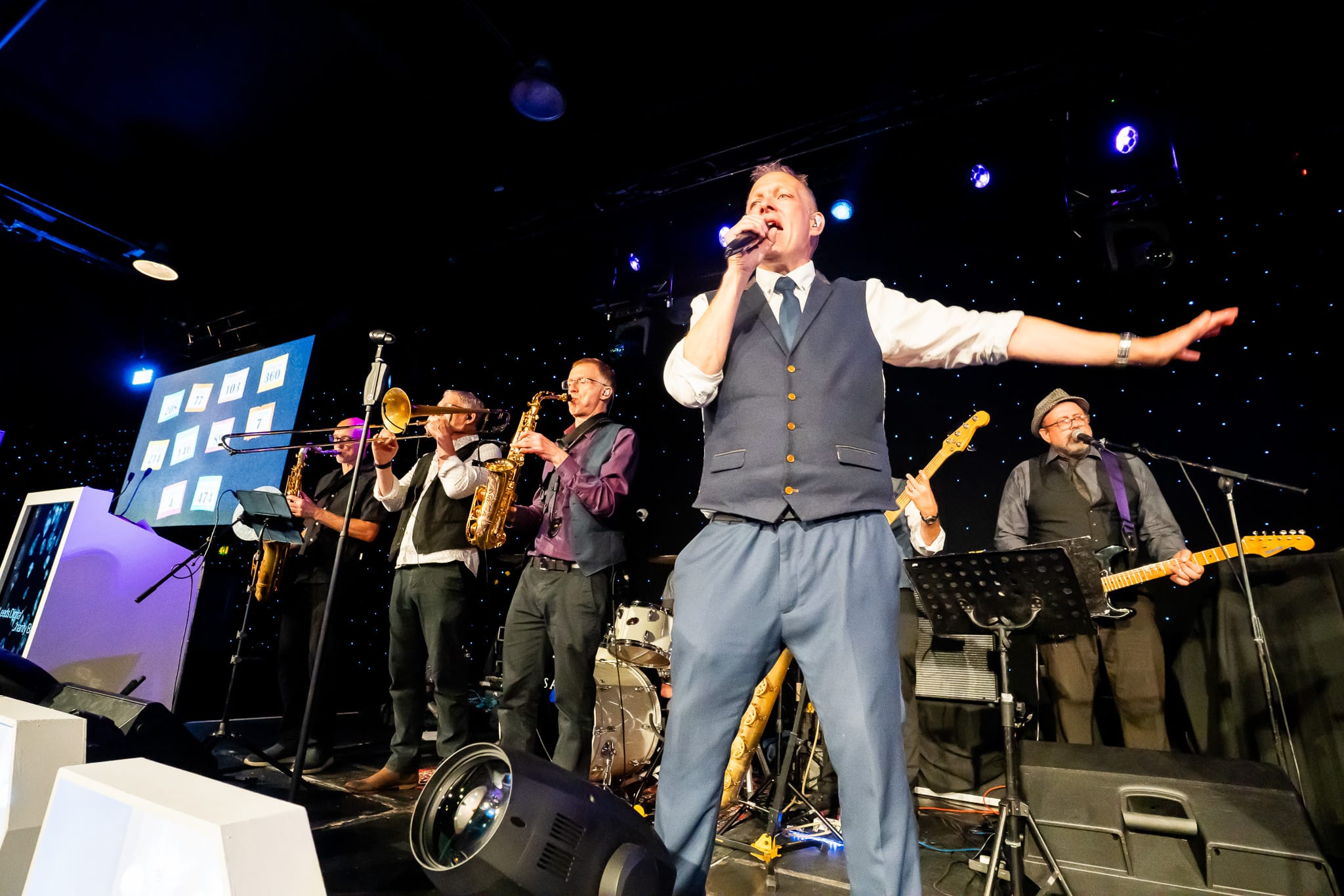 A singer performing with a live band at a charity ball