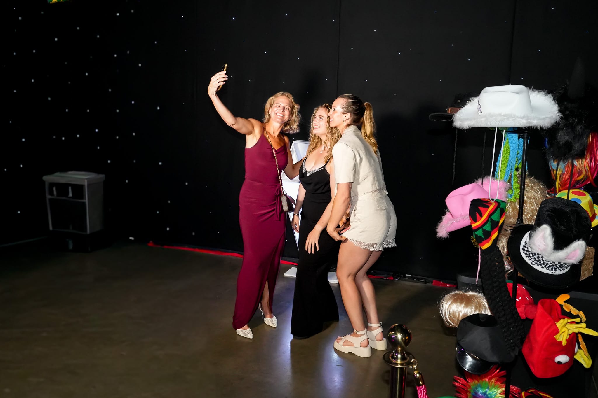 Friends posing playfully with props at the photo booth
