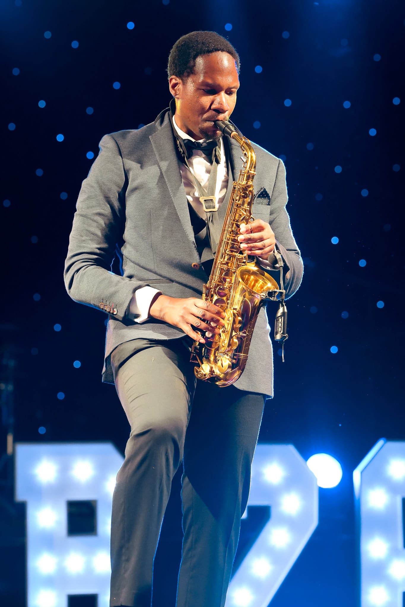 A saxophonist playing under the stage lights