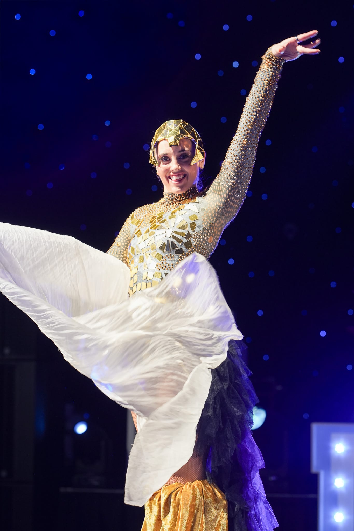 A costumed dancer performing with a flowing white fan on stage