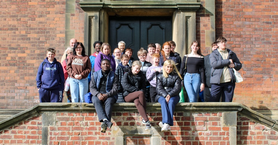 A group of young people and adults gathered on the steps of a red-brick building
